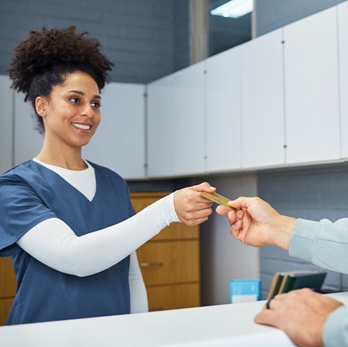 Man handing payment card at counter to woman in scrubs