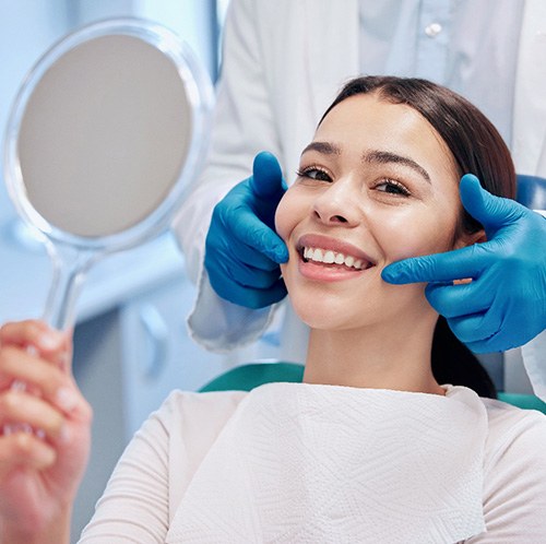 Patient smiling while holding small mirror