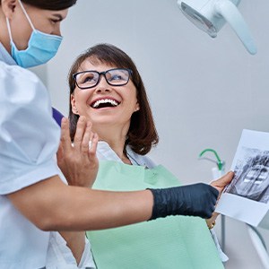 Woman smiling with dentist while reviewing X-ray
