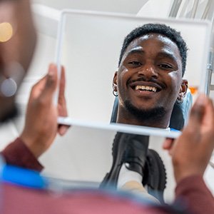 Young man smiling in the mirror at the dentist’s office