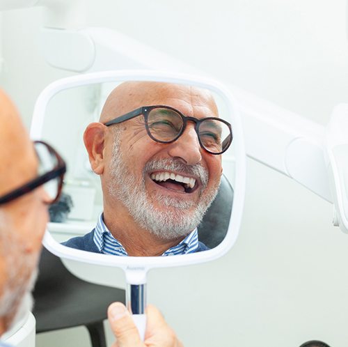 Man with black glasses smiling in reflection in mirror