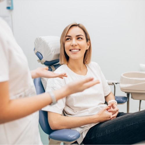 Man in dental chair smiling while dental team member puts cloth in place