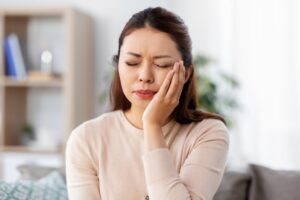 Woman holding mouth in pain. 