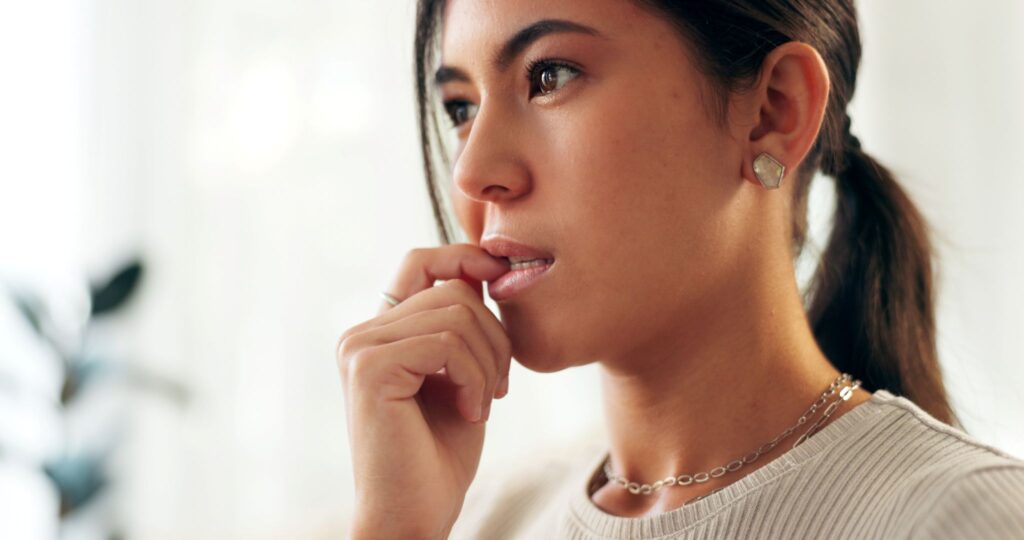 Woman with ponytail chewing her fingernail